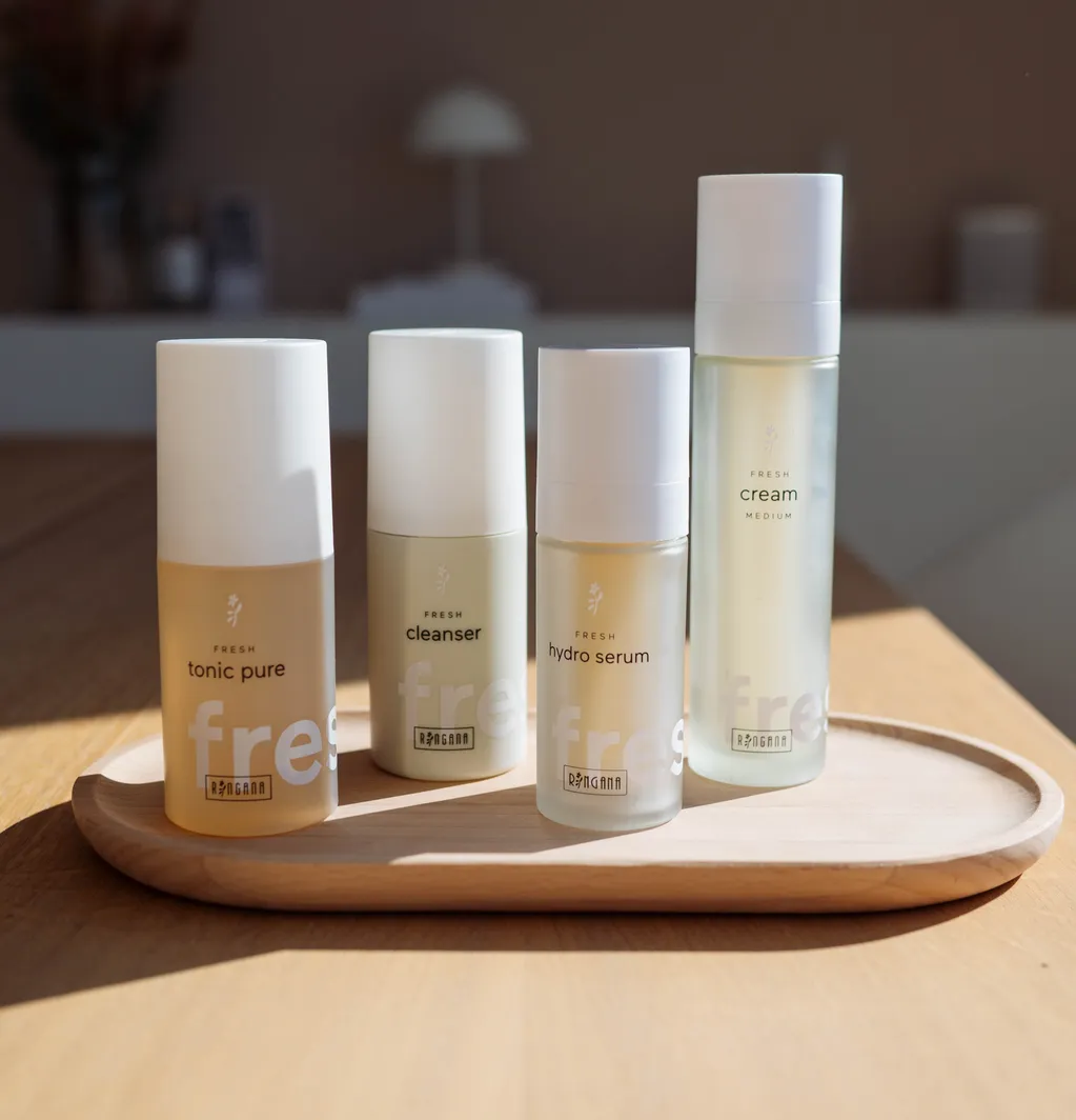RINGANA FRESH Tonic Pure, Cleanser, Hydro Serum und Cream Medium auf einem Holztablett im warmen Sonnenlicht.